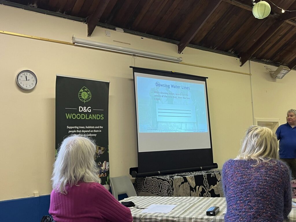 Participants looking at a slide about 'dowsing water lines' at D&G Woodlands workshop on dowsing at Mossdale Village Hall